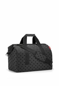 Black duffel bag with a polka dot pattern, featuring sturdy fabric, dual handles, and an adjustable shoulder strap. Zipper closure.
