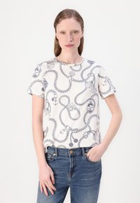 Hvid t-shirt med korte ærmer, prydet med marineblå snor og nautisk tema. Rund hals, afslappet pasform, blødt bomuldsstof. Båret med blå jeans.