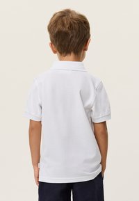 Λευκό πόλο πουκάμισο με κοντά μανίκια, κλασικό γιακά, απαλό βαμβακερό ύφασμα και ετικέτα στη αριστερή πλευρά. Προβολή από πίσω.