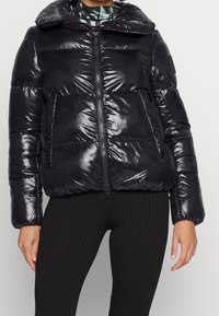 Giubbotto imbottito nero con finitura lucida, colletto oversize, chiusura frontale con zip e due grandi tasche, con polsini e orlo a costine.