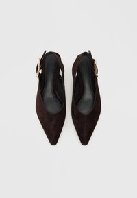 Dark brown suede slingback shoes with a pointed toe, featuring a cutout design and a gold-tone buckle accent. Flat sole interior.