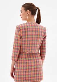 Plaid dress in multicolor hues of pink, yellow, and green. Features a fitted waist and three-quarter sleeves, made of textured fabric.