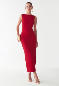Punane ilma varrukat maxi kleit sirge dekoltee ja figuuri järgiva siluetiga. Kombineeritud kuldsete kontsakingade ja kuldsete aksentidega käekotiga. Sile tekstuur.