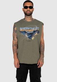 Ärmlös olivgrön t-shirt med en blå örn-grafik och text. Tyget verkar mjukt med en avslappnad passform.