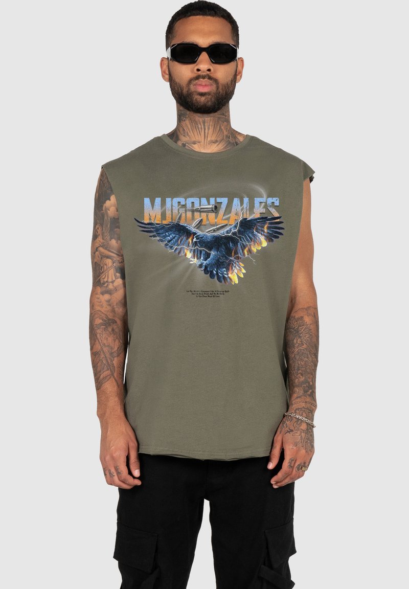 Ärmlös olivgrön t-shirt med en blå örn-grafik och text. Tyget verkar mjukt med en avslappnad passform.