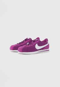 Ljubičaste Nike tenisice s teksturiranim gornjim dijelom, bijelim Swoosh logom, zaobljenim vrhom i gumenim đonom. Imaju vezice i podstavljeni ovratnik.