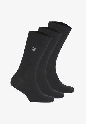 Drei Paar schwarze Sportsocken mit einem kleinen grauen Logo an der äußeren Seite nahe der oberen Manschette, nebeneinander angeordnet.