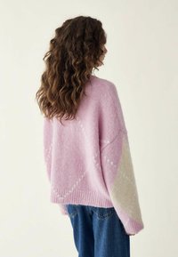 Übergroßer, rosa- und cremfarbener Pullover mit langen, strukturierten Ärmeln und lockerer Passform; verfügt über ein Rautenmuster und einen gerippten Saum.