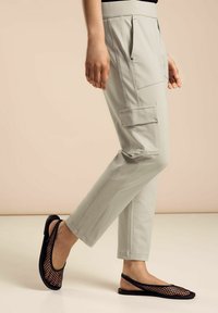 Ljusgrå cargobyxor med slim fit, sidofickor och en slät yta, ihop med svarta mesh-skor som är lätta att ta på.