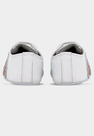 Λευκά παπούτσια μωρού με μαλακή σόλα, φαίνονται από πίσω, με ραμμένη κάθετη ραφή και σχέδιο καρτούν αρκουδάκι στις πλευρές.