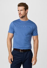 T-shirt en coton bleu avec col rond, présentant une bordure blanche contrastante et le mot "HACKETT" imprimé en blanc sur la poitrine.