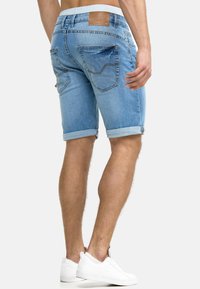 Denim šorci svijetloplave boje s prevrnutim rubom. Sadrže dva stražnja džepa i markirani smeđi kožni logotip na pojasu.