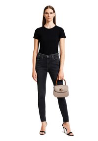 Maglietta nera aderente, jeans scuri a vita alta, sandali neri con tacco alto e una borsa grigia chiara con manico in bambù.