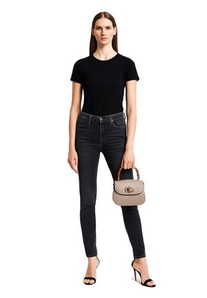 T-shirt noir ajusté, jeans noirs taille haute, sandales à talons hauts noires, et un sac à main gris clair avec une poignée en bambou.