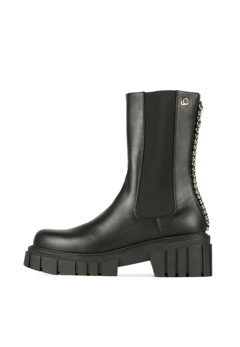 Botín negro de cuero con paneles laterales elásticos, suela plataforma gruesa y detalle decorativo de cadena en la parte trasera. Textura suave, diseño robusto.