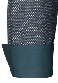 Manica di camicia blu con pattern, caratterizzata da un design a diamanti di blu scuro e blu chiaro, con un polsino verde scuro uniforme. Morbida al tatto.