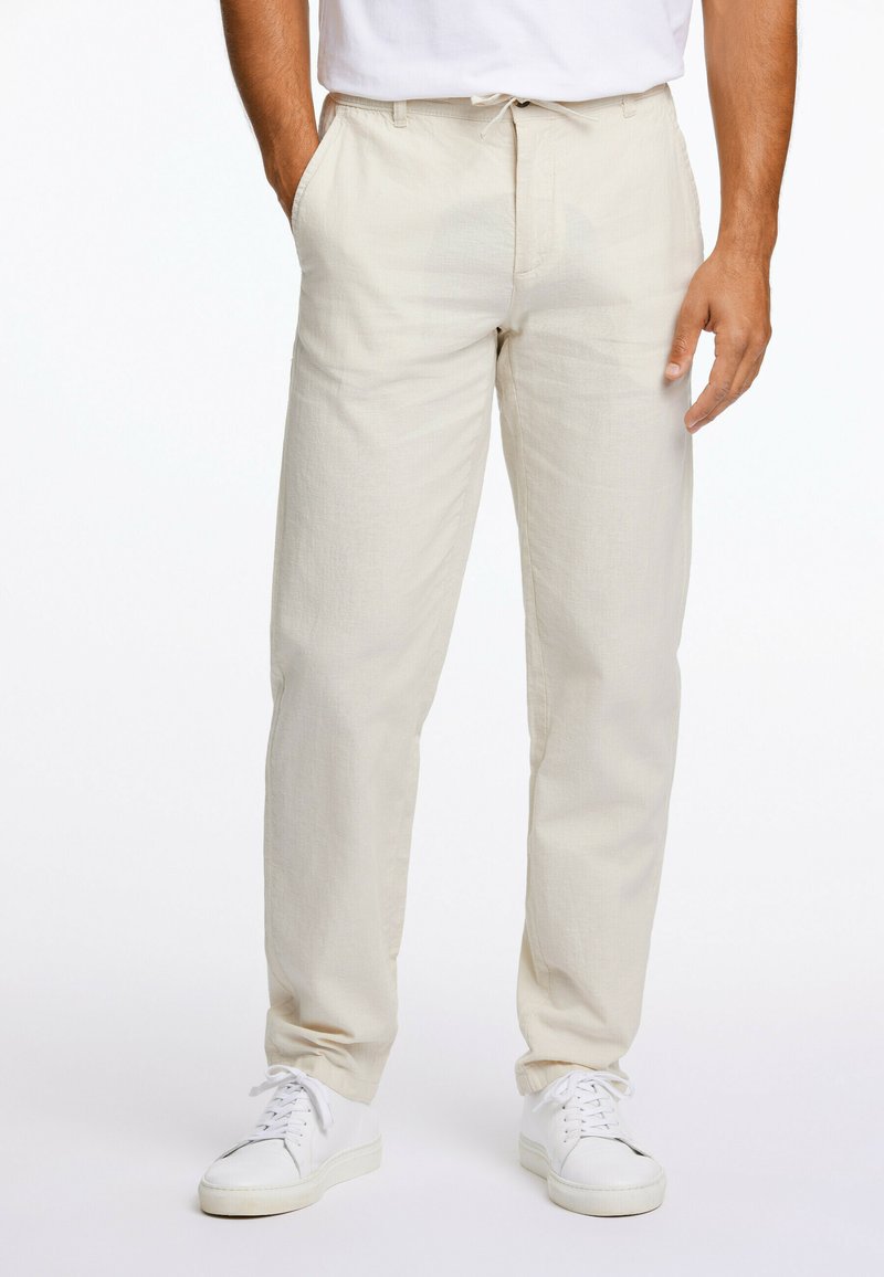 Lys beige chinos med rett snitt, laget av teksturert stoff, med sidelommer og strammere i livet. Matchet med hvite sneakers.