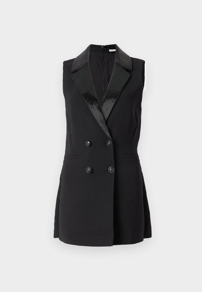 Chaleco negro sin mangas con frente de doble botonadura, solapas negras brillantes, dos bolsillos frontales y una textura de tela que parece suave.