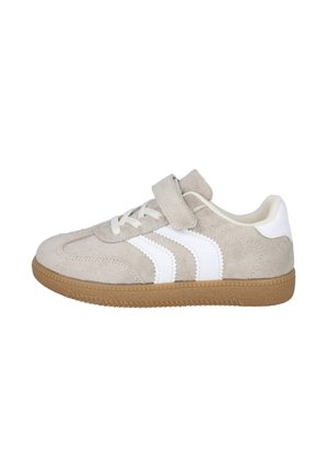 Zapatilla de ante beige con rayas blancas en los lados, suela de goma marrón, cordones y una tira de velcro en la parte superior para abrochar.