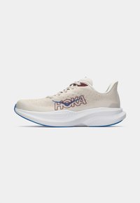 Sapatilha de corrida em malha bege claro com o logótipo HOKA em vermelho e azul. Sola intermédia alta e acolchoada em branco com um destaque azul na sola.
