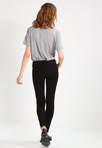 Grå bomullströja med korta ärmar som matchas med svarta skinny jeans. Jeansen har en figursydd siluett och minimal detaljering.
