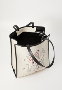 Canvas toteväska med svart läderdetaljer, har illustrerade mönster i röd och svart. Inuti finns en ficka med blixtlås och beige foder.