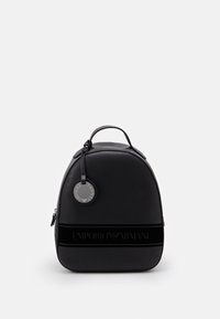 Black backpack with a rounded design, made of smooth leather. Features a logo band, silver hardware, and a round tag attached to the handle.