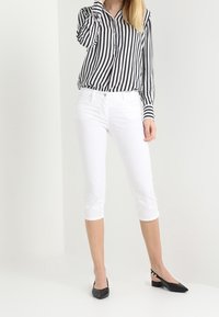 Black and white striped button-up shirt, white cropped pants, and black flats with straps. Smooth fabric, tailored fit, and classic design.