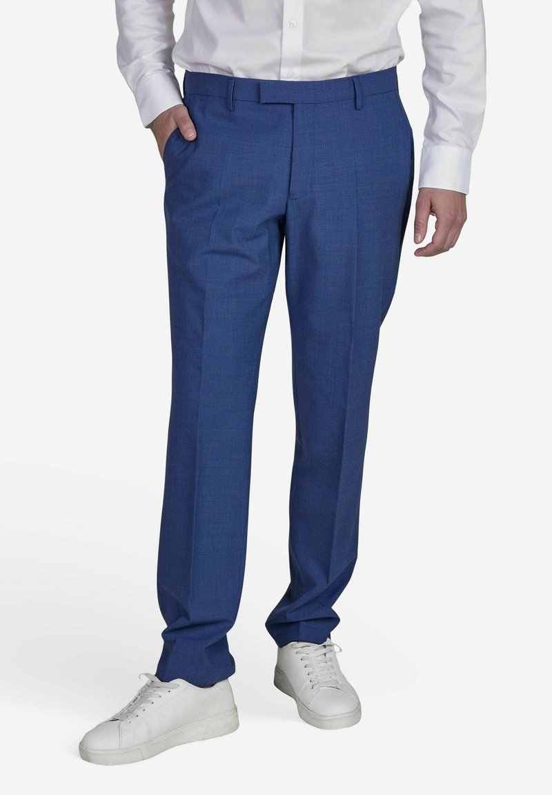 Blaue Anzughosen mit einem dezenten Muster, aus einem leichten Stoff gefertigt, haben eine taillierte Passform, seitliche Taschen und werden mit weißen Sneakers kombiniert.