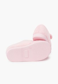 Zapatillas de casa rosas, peludas y con una textura suave, punta redondeada y tacón bajo. La suela es de goma lisa y con un patrón, con un mínimo de agarre.