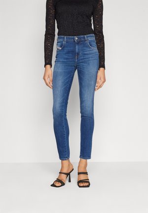 Jeans in denim blu a vita alta, slim-fit, con un leggero sbiadimento, dotati di cinque tasche e chiusura a bottoni. Abbinati a un top a maniche lunghe in pizzo nero.