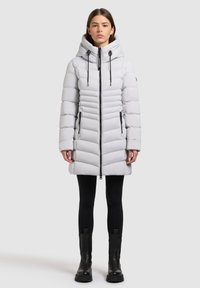 Světlý šedý péřový kabát s vertikálním prošíváním, vysokým límcem, nastavitelnými stahovacími šňůrkami, bočními kapsami na zip a délkou po střed stehen.