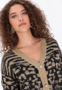 Barna és fekete állatmintás kardigán V-nyakkal, flitterekkel díszítve és két átlátszó drágakő gombbal az elején.