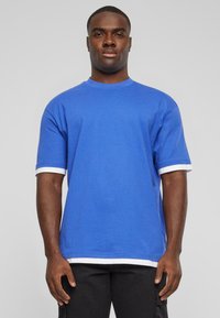 T-shirt en coton bleu à manches courtes avec des bordures blanches aux poignets et à l'ourlet. Design classique à col rond. Sans motifs ni graphiques.