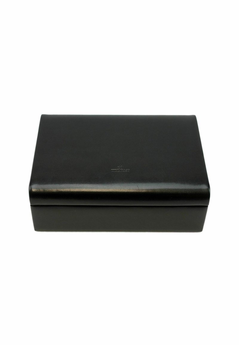 Boîte rectangulaire en cuir noir avec une texture lisse, des bords légèrement arrondis et un logo embossé simple sur la surface supérieure.