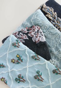 Cuatro piezas de textil de punto en diferentes tonos de azul, con patrones florales en blanco, marrón y verde. Cada una presenta texturas y diseños únicos.