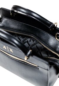 Borsa a mano in pelle nera con doppio manico, zip dorata e interno a fantasia con marchio. Texture liscia e forma strutturata.