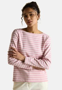 Długi rękaw bluzka w jasnoróżowym kolorze z białymi poziomymi paskami. Miękka tkanina, dekolt w łódkę i szyte mankiety. Prosty design bez ozdób.