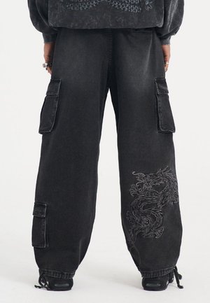 Sorte denim cargo bukser med store sidelommer, der har en detaljeret dragebroderi på venstre ben og en løs pasform.