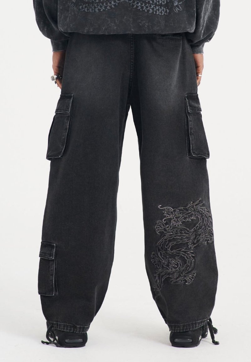 Pantalones cargo de denim negro con grandes bolsillos laterales, con un bordado detallado de un dragón en la pierna izquierda y un diseño holgado.