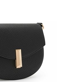 Bolso cruzado de cuero negro con un acabado texturizado, cierre de solapa curvada y detalle de hardware rectangular en dorado. Forma compacta y redondeada.