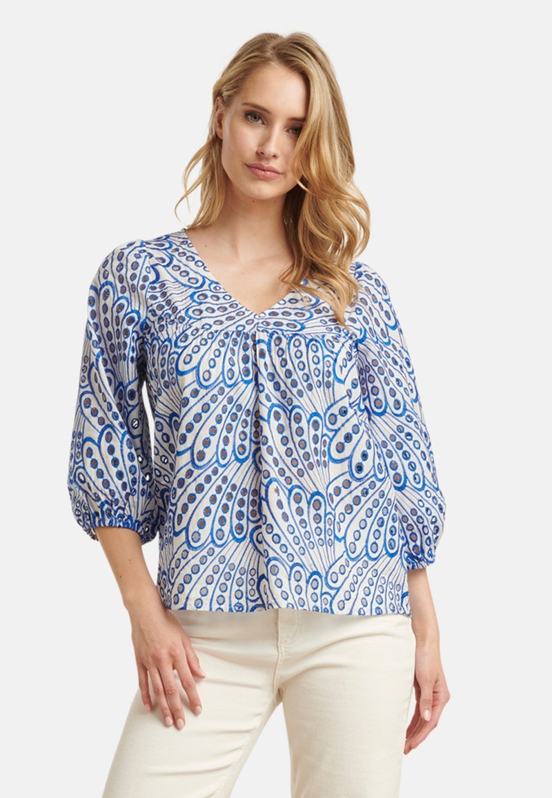 Blauw en wit gebloemde blouse met een V-hals, poffende mouwen en een losse pasvorm, met een bloemenpatroon en subtiele textuur.