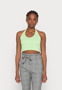Top cropped halter de riscas verde claro com decote redondo, combinado com calças de cintura alta cinza em padrão xadrez, apresentando um detalhe de laço na cintura.