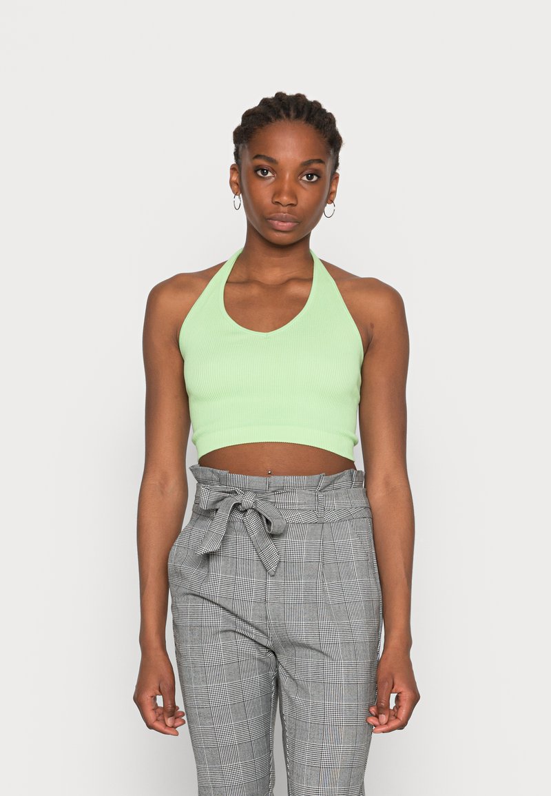 Top cropped halter de riscas verde claro com decote redondo, combinado com calças de cintura alta cinza em padrão xadrez, apresentando um detalhe de laço na cintura.