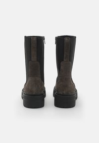 Brown suede ankle boots with black elastic sides, featuring a back pull tab and zip closure for easy wear. Thick black rubber soles.