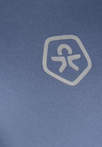 Blått textil har en texturerad yta med en subtil lyster. Designen inkluderar ett ljusgrått emblem som föreställer en stiliserad figur inom en hexagon.