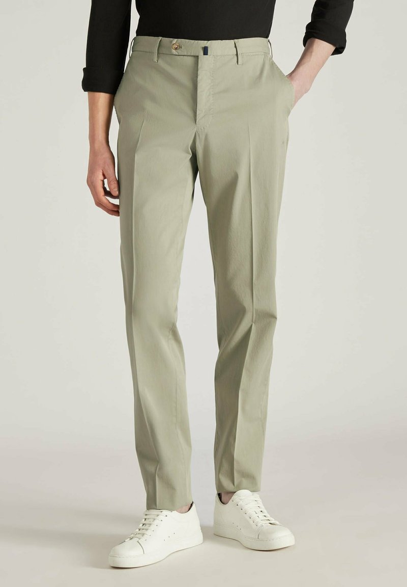 Lichtgroene gepaste broek van gladde stof, met een ritssluiting en knoopsluiting, zijzakken en een slim fit, gedragen met witte sneakers.