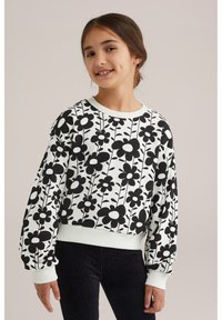 Čierny kvetinový sveter s nadrozmernými rukávmi a bielymi manžetami, ktorý má monochromatický kvetinový vzor na svetlom pozadí.