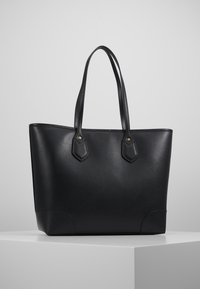 Sac fourre-tout en cuir noir avec deux longues poignées, forme rectangulaire, surface texturée et subtils éléments métalliques dorés sur la poignée.