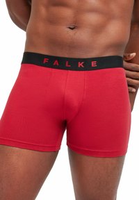 Boxers rouges en tissu doux, avec une taille noire portant le logo "FALKE" en rouge, conçus pour le confort et l'ajustement.